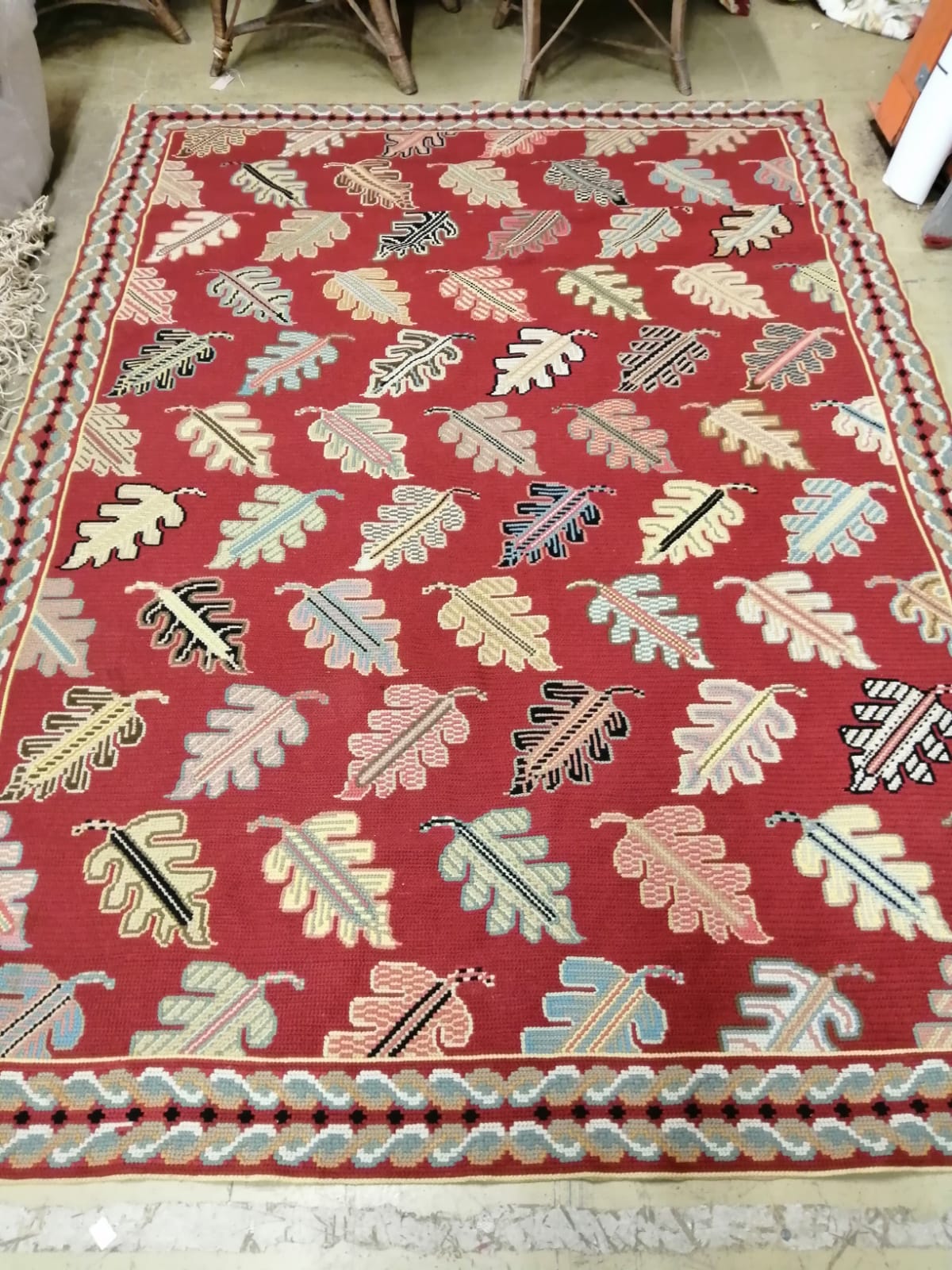 A Portuguese polychrome red ground rug woven with stylised leaves 236cm x 170cm.